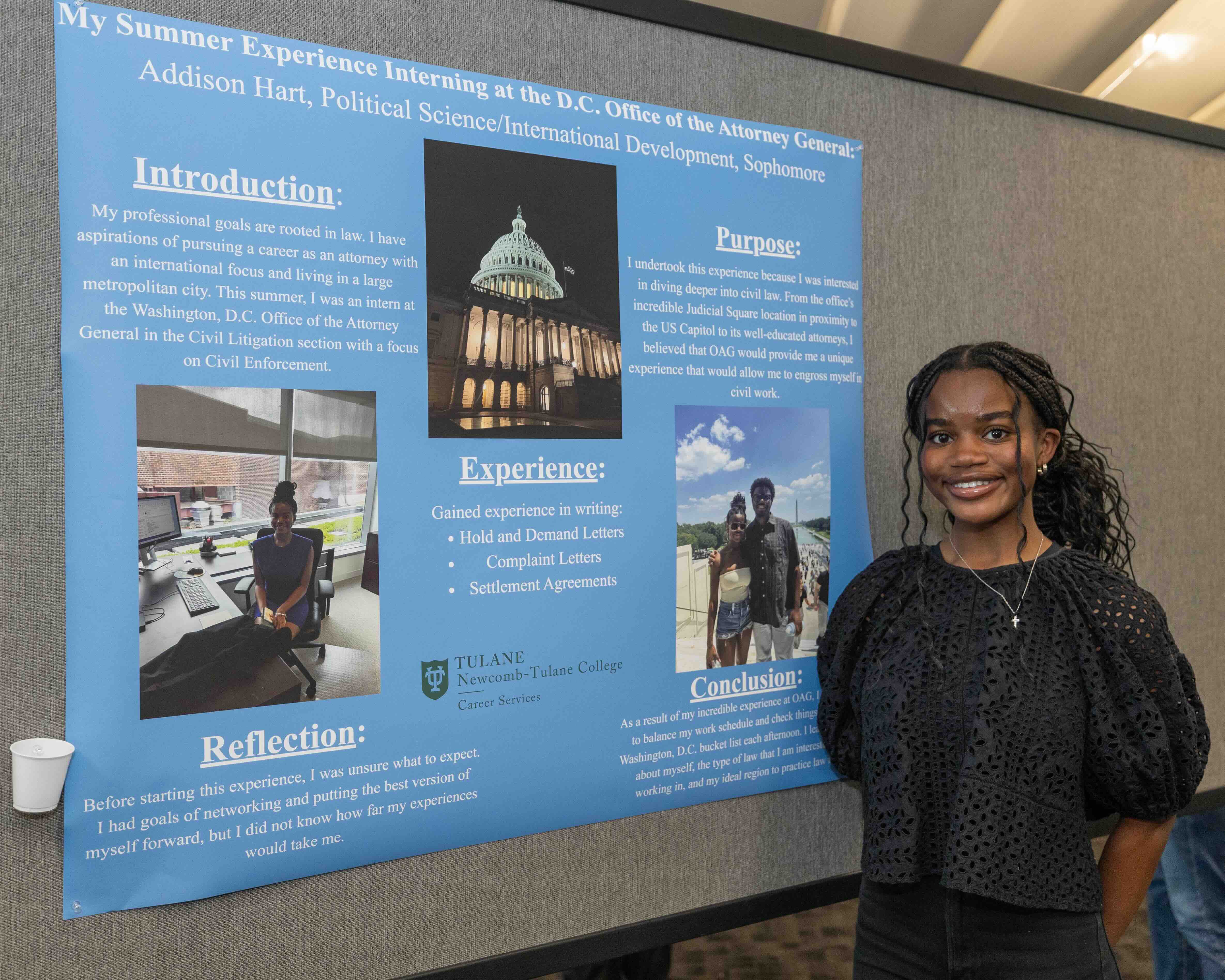 Smiling woman poses next to a blue academic poster about "My Summer Experience."