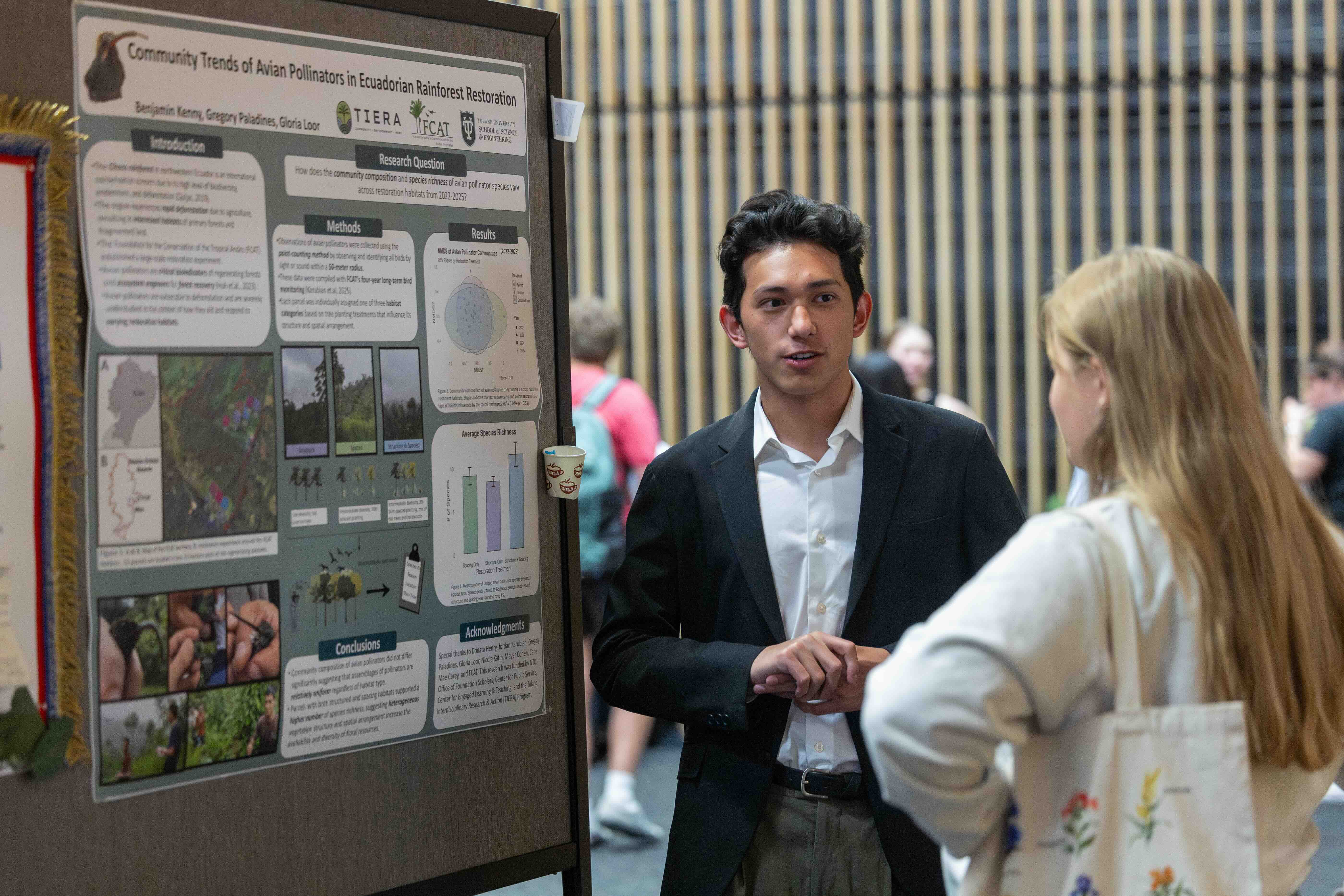 Student presenting a research poster to another student at an academic event.