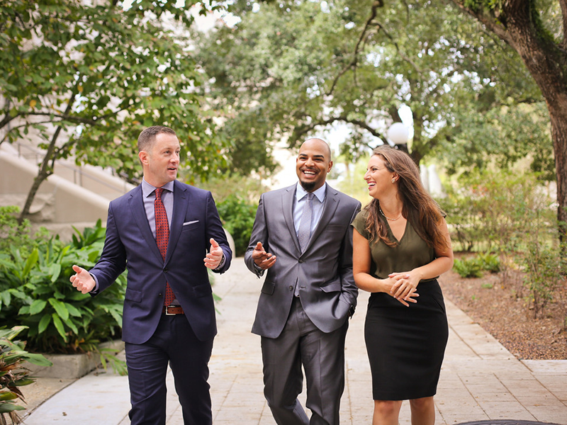 a white man, black man, and white woman in professional attire walking 