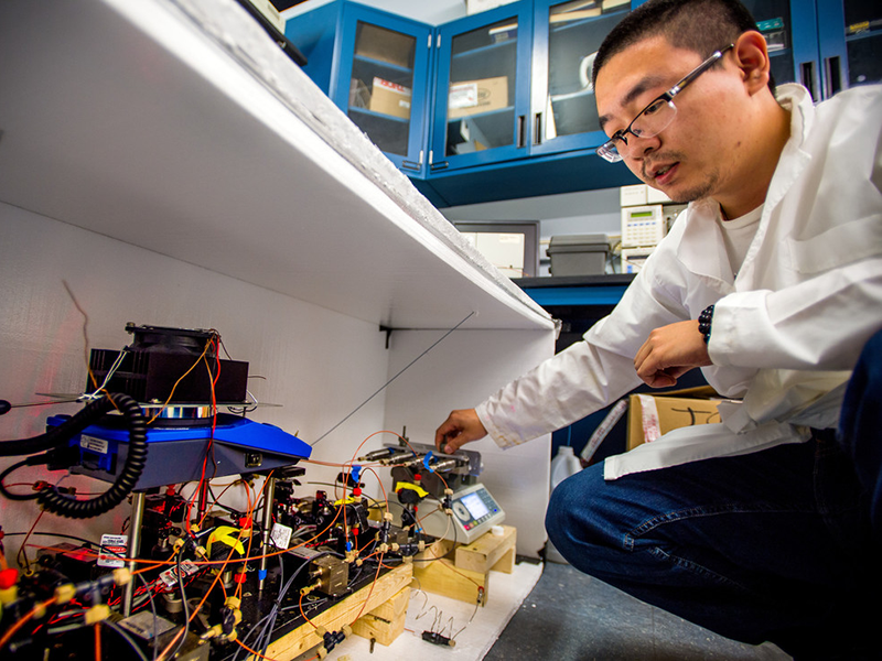 Aide Wu, a Postdoctoral Research Fellow in materials science, works with a second generation automatic continuous online monitoring of polymerization reactions instrument (ACOMP)